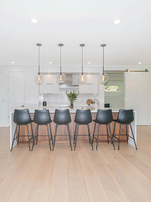 A remodeled kitchen with island and hanging lights.