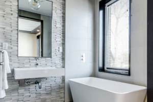 A remodeled bathroom with grey tile and white tub.